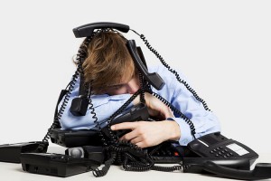 Exhausted man sitting with a bunch of phones over him